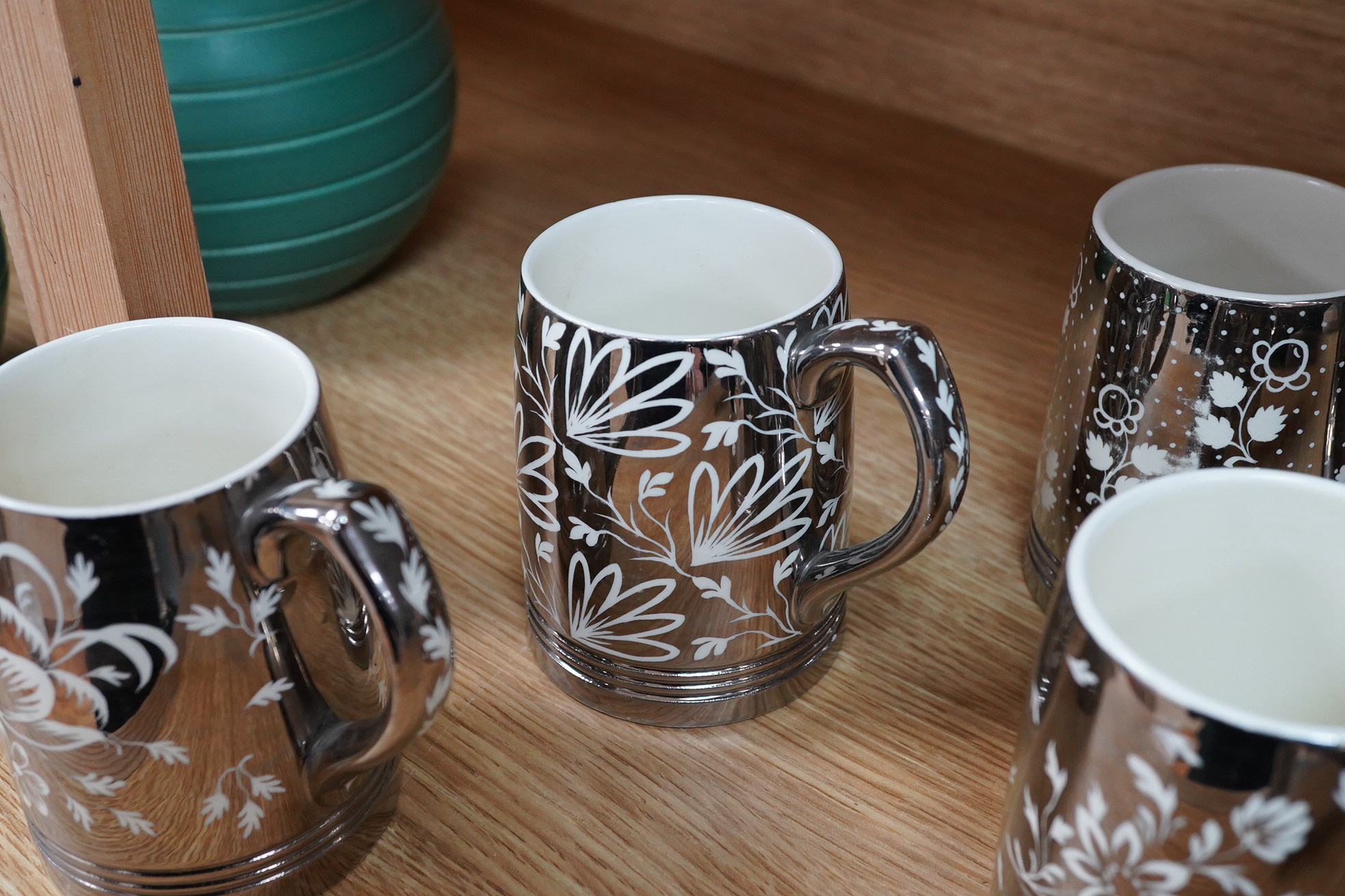 Keith Murray for Wedgwood, a set of four silvered mugs, decorated by Millicent Taplin, largest 10cm high